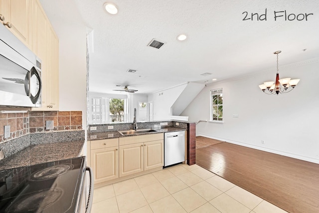 kitchen featuring visible vents, a sink, backsplash, appliances with stainless steel finishes, and a peninsula