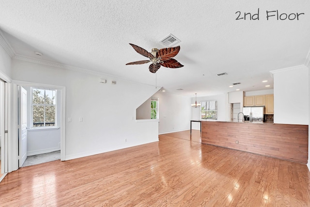 unfurnished living room with light wood-style flooring, a healthy amount of sunlight, and visible vents