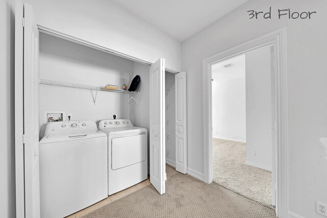 clothes washing area with visible vents, baseboards, light carpet, laundry area, and separate washer and dryer