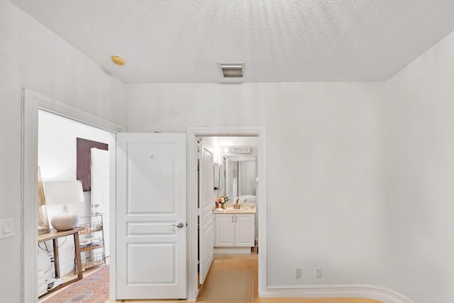 hallway featuring a sink, visible vents, and a textured ceiling