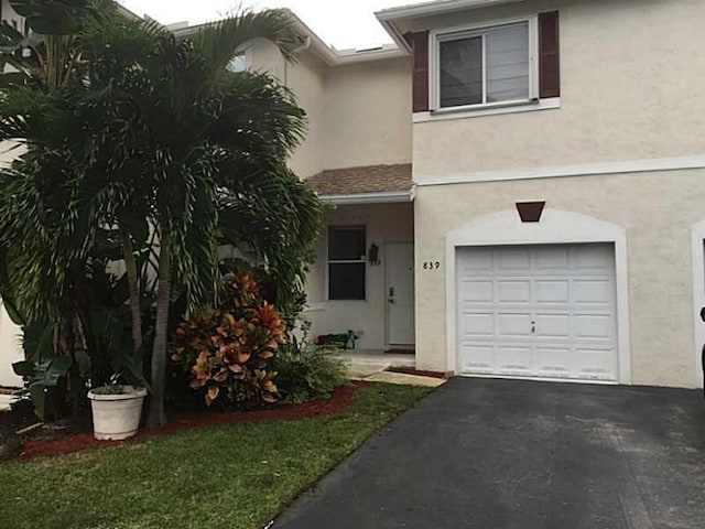 view of front of property with aphalt driveway, an attached garage, and stucco siding