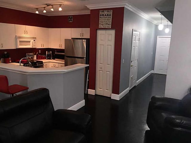 kitchen with white microwave, a peninsula, white cabinets, light countertops, and freestanding refrigerator