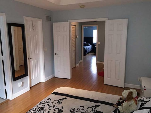 bedroom with visible vents, baseboards, and wood finished floors