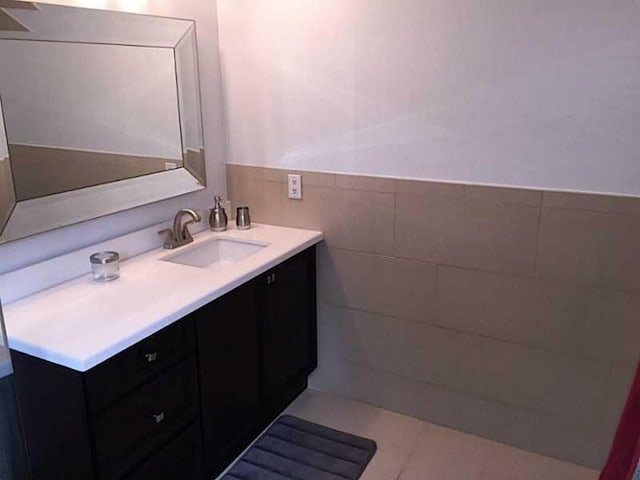 bathroom featuring wainscoting, vanity, and tile walls