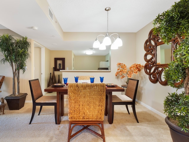 dining space with light carpet, a chandelier, baseboards, and visible vents