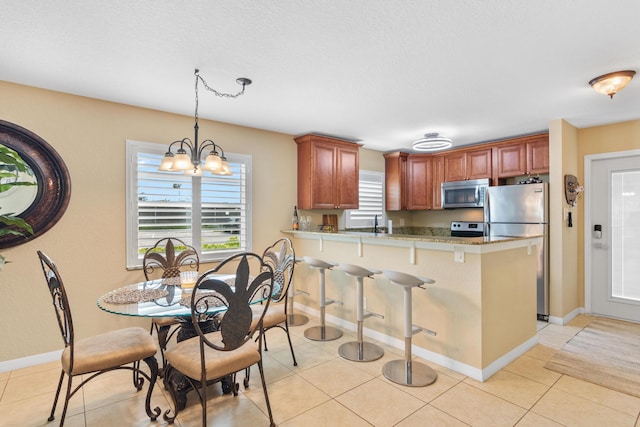 kitchen featuring light tile patterned floors, an inviting chandelier, a peninsula, light countertops, and appliances with stainless steel finishes