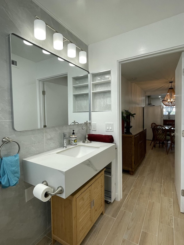 bathroom featuring visible vents, tile walls, wood tiled floor, decorative backsplash, and vanity