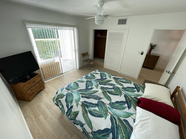 bedroom with visible vents, a textured ceiling, a closet, light wood finished floors, and ceiling fan