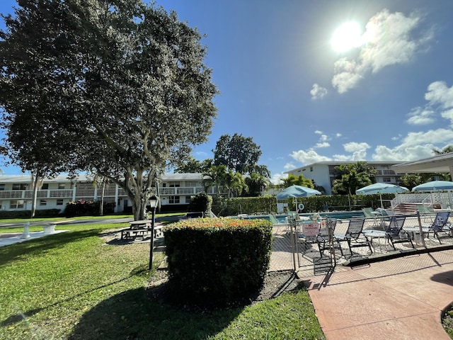 view of home's community with a pool, a lawn, a patio, and fence