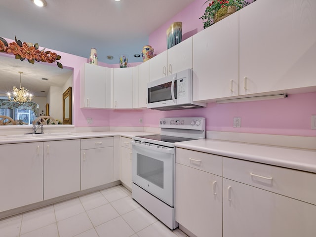 kitchen featuring white appliances, light countertops, a sink, and white cabinets