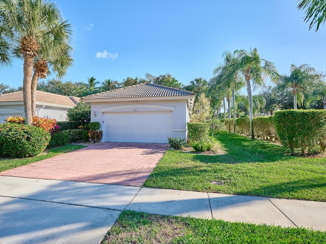 view of front of property with a garage, a tile roof, decorative driveway, a front yard, and stucco siding