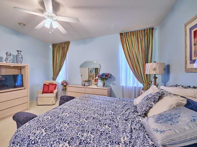 carpeted bedroom featuring ceiling fan and a textured ceiling