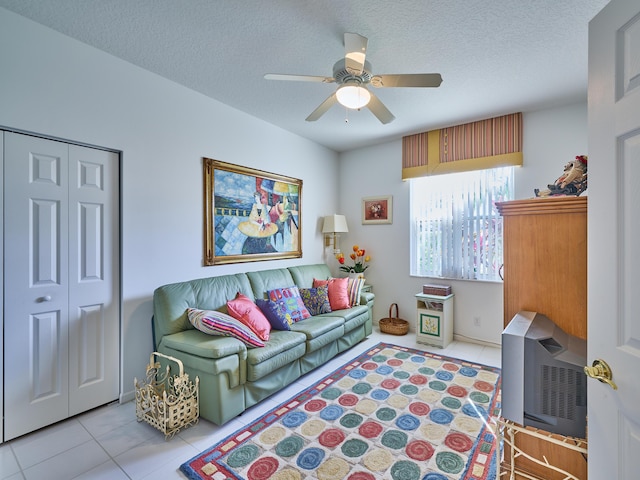 living area featuring tile patterned flooring, ceiling fan, and a textured ceiling