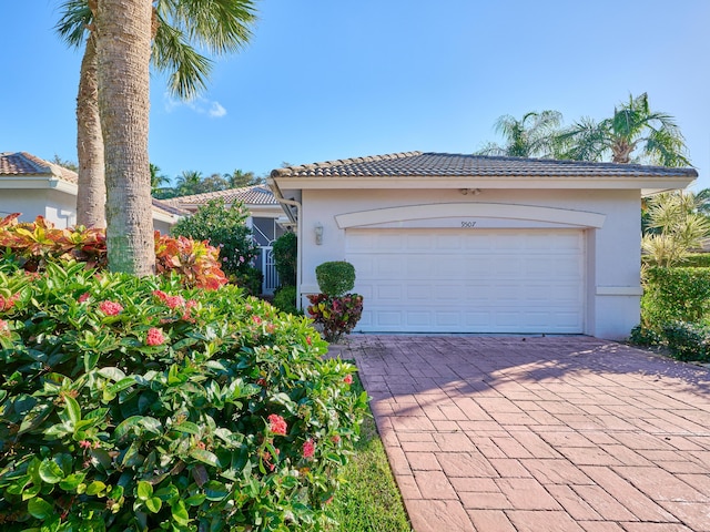 view of front of house featuring decorative driveway, a tile roof, and stucco siding