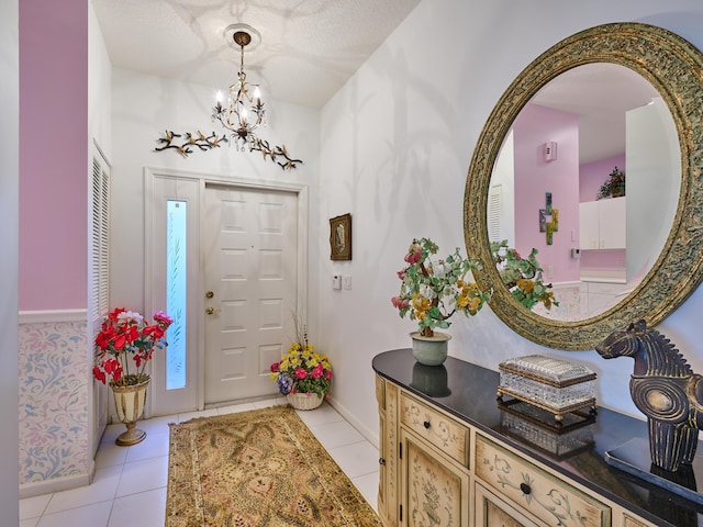 foyer featuring a chandelier, baseboards, and light tile patterned floors