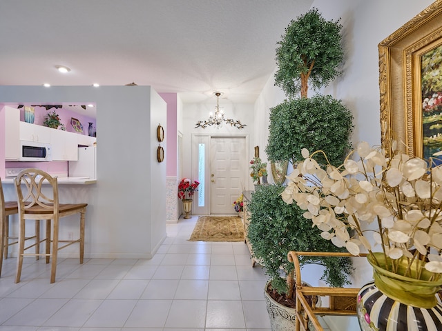 entrance foyer featuring baseboards, light tile patterned flooring, and an inviting chandelier