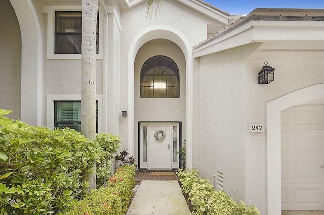 doorway to property featuring a garage and stucco siding