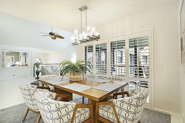 tiled dining space with lofted ceiling, baseboards, and ceiling fan with notable chandelier