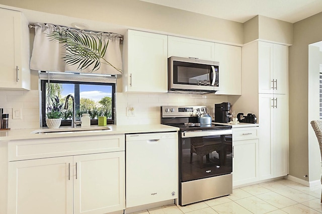 kitchen featuring stainless steel appliances, a sink, light countertops, and white cabinets