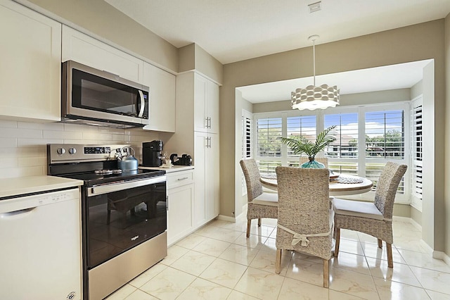 kitchen with stainless steel appliances, marble finish floor, white cabinetry, and backsplash