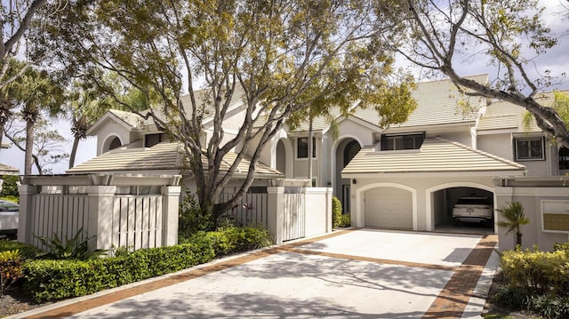 view of front facade with stucco siding, an attached garage, fence, driveway, and a tiled roof