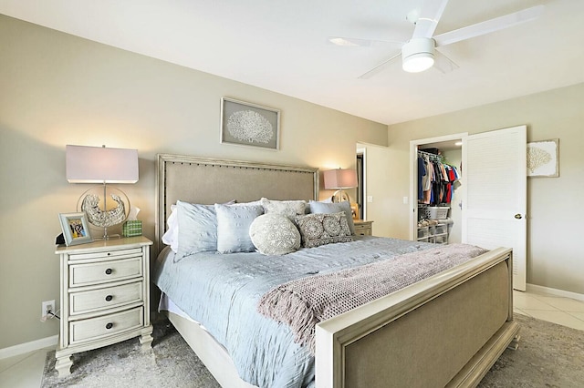 bedroom with light tile patterned floors, a spacious closet, a ceiling fan, and baseboards