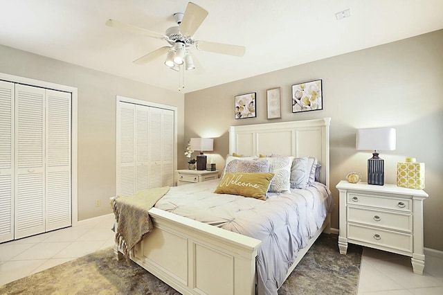 bedroom with ceiling fan, baseboards, multiple closets, and light tile patterned flooring