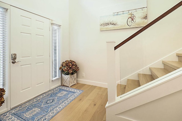 foyer featuring stairs, plenty of natural light, wood finished floors, and baseboards