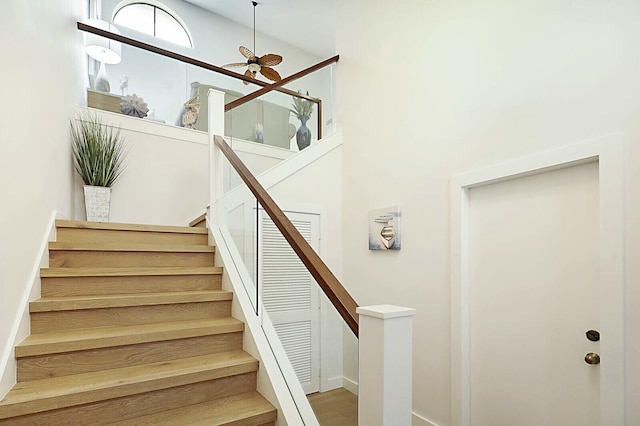 staircase with a towering ceiling and a ceiling fan