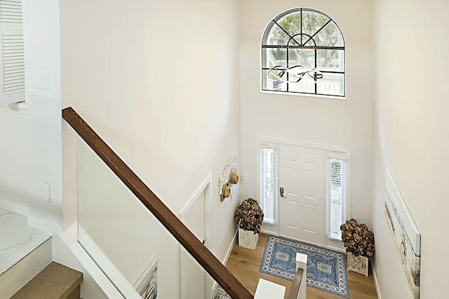 foyer with stairway, a towering ceiling, and wood finished floors