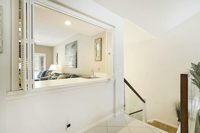 hallway featuring an upstairs landing, a sink, and baseboards