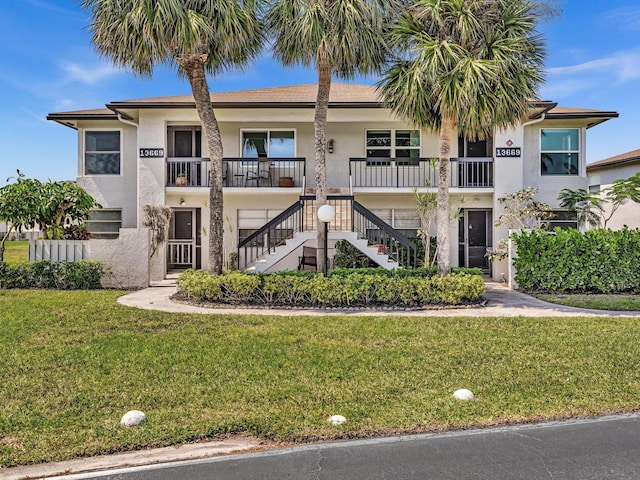 multi unit property featuring stairs, a front yard, and stucco siding