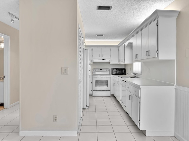 kitchen with under cabinet range hood, a textured ceiling, white appliances, light countertops, and light tile patterned floors