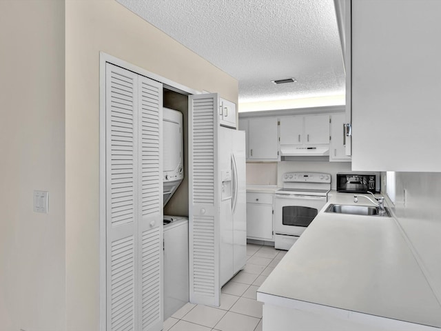 kitchen with visible vents, under cabinet range hood, a sink, stacked washing maching and dryer, and white appliances