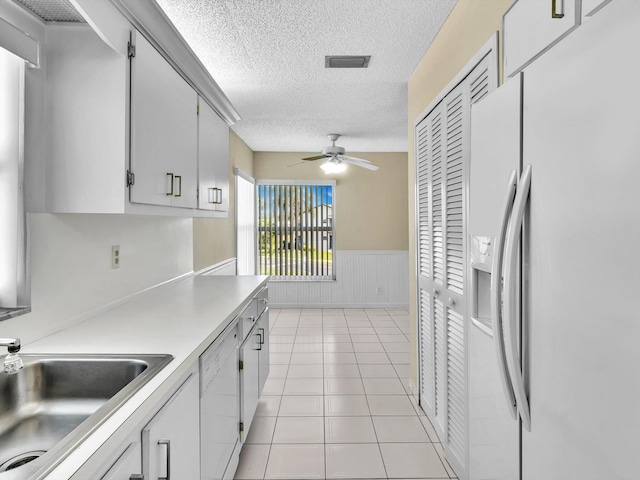 kitchen featuring visible vents, light countertops, wainscoting, white appliances, and a sink