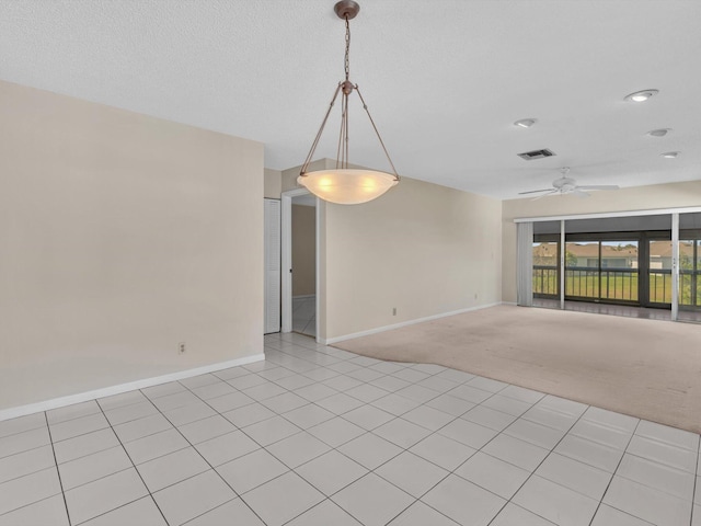 spare room featuring visible vents, light colored carpet, baseboards, and ceiling fan