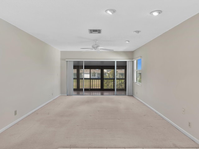 carpeted empty room with a ceiling fan, a healthy amount of sunlight, visible vents, and baseboards