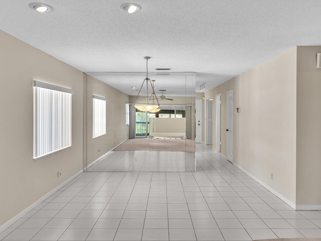 spare room with baseboards, a textured ceiling, and light tile patterned flooring