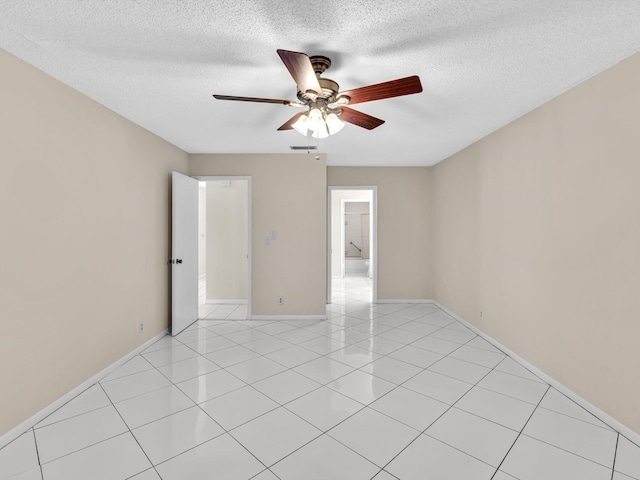 unfurnished room with visible vents, baseboards, light tile patterned floors, a textured ceiling, and a ceiling fan