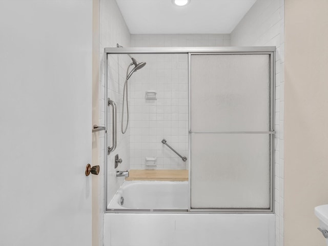 full bath featuring toilet and shower / bath combination with glass door