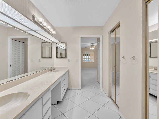 full bath with double vanity, a sink, a closet, a textured ceiling, and tile patterned floors