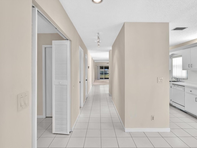 corridor with light tile patterned flooring, visible vents, and a textured ceiling