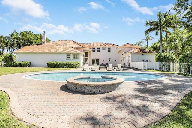 view of pool featuring a pool with connected hot tub, a patio area, and fence