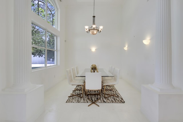 dining room featuring ornate columns, plenty of natural light, a towering ceiling, and an inviting chandelier