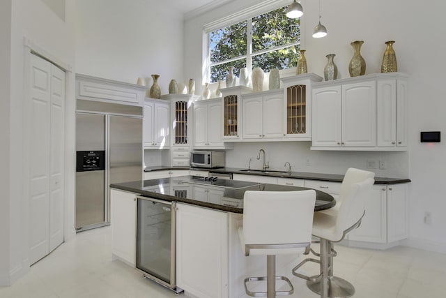 kitchen featuring wine cooler, built in fridge, a sink, white cabinetry, and dark countertops