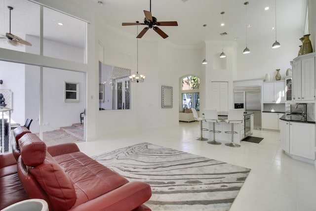 living room with recessed lighting, a high ceiling, ornamental molding, and ceiling fan with notable chandelier