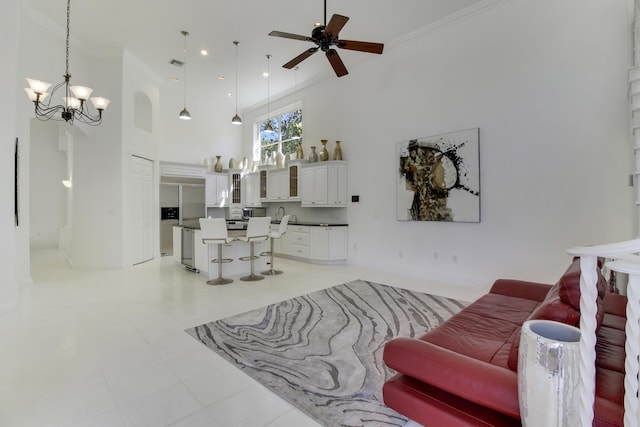 living area featuring ceiling fan with notable chandelier, a high ceiling, visible vents, and crown molding