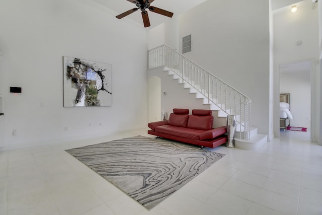 tiled living area with ceiling fan, a high ceiling, stairway, and arched walkways