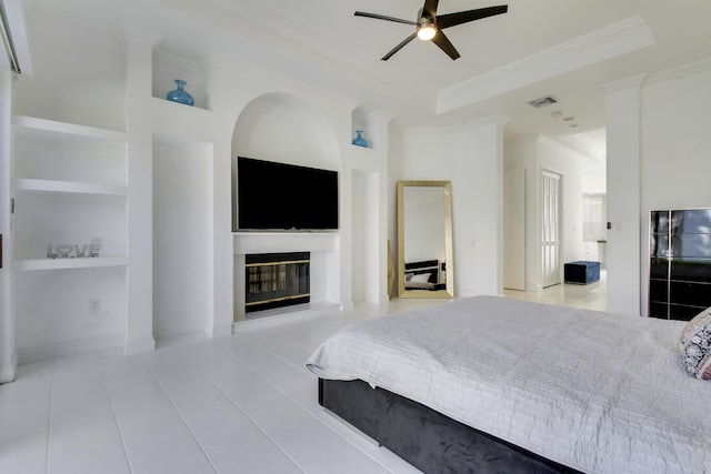 tiled bedroom with a ceiling fan, visible vents, a tray ceiling, a glass covered fireplace, and crown molding