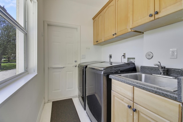 clothes washing area featuring a healthy amount of sunlight, cabinet space, separate washer and dryer, and a sink